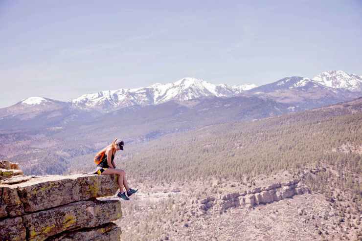 photography of a woman sitting on cliff